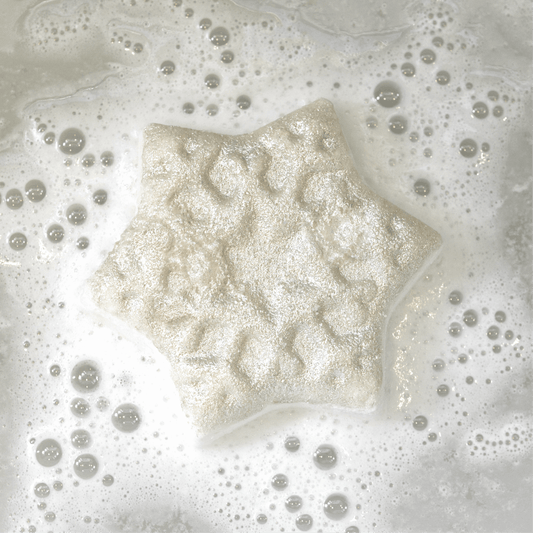 Snow Flake shaped bath bomb handcrafted by Pacha Soap and in the "Balsam & Pine" Scent. Fizzling out in the tub.