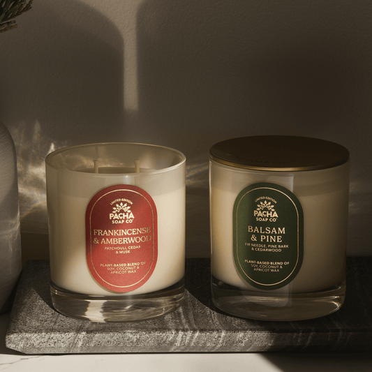 Pacha Soap Co's Frankincense & Amberwood and Balsam & Pine Signature Candles in a intense lighting and on a marble tray
