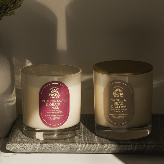 Pacha Soap Co's Pomegranate & Orange Peel and Vanilla Bean & Clove Signature Candles in a intense lighting and on a marble tray