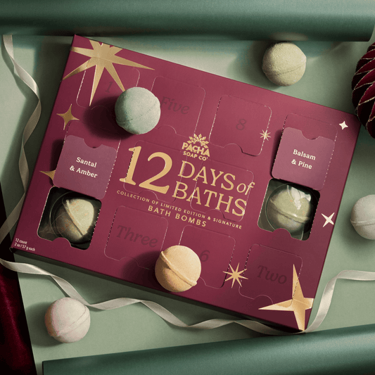 12 Days of Baths Advent Calendar with Handcrafted bathbombs made by Pacha Soap Co in a beautiful setting with bath bombs scattered around it, all along with ornaments and ribbon