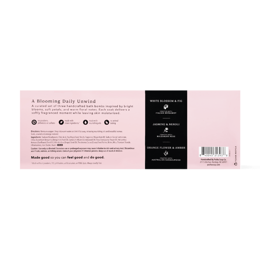 The back of a bath bomb package showing product details, ingredients, and a barcode. The design features a soft pink background with a black vertical column on the right containing white text for 'White Blossom & Fig', 'Jasmine & Neroli', and 'Orange Flower & Amber'.