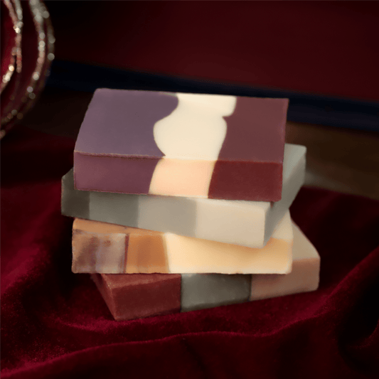 Four multicolored barsoaps from Pacha Soap Co.'s Holiday barsoap Set on a deep burgundy velvet.
