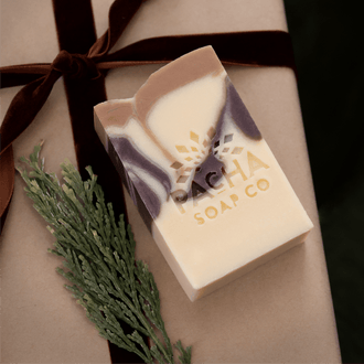 Pacha Soap Co. Brown and cream bar soap surrounded by ribbon and a pine sprig.