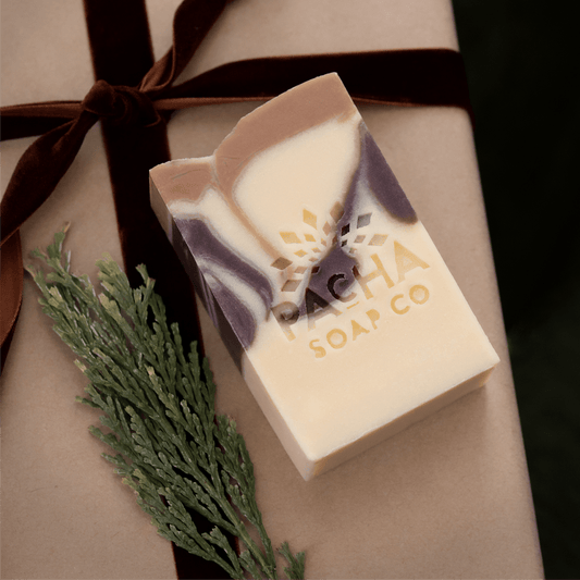 Pacha Soap Co. Brown and cream bar soap surrounded by ribbon and a pine sprig.