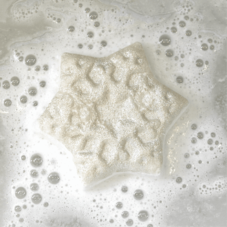 Snow Flake shaped bath bomb handcrafted by Pacha Soap and in the "Balsam & Pine" Scent. Fizzling out in the tub.