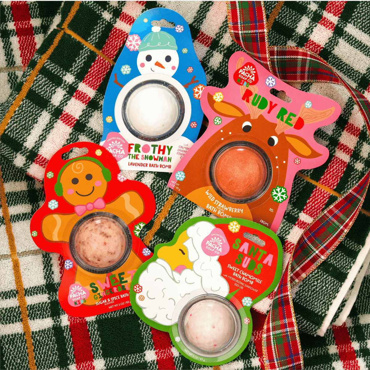 Pacha Soap Kid's Bath bomb cards "FROTHY THE SNOWMAN," "RUDY RED," "SWEET GINGER BREAD," and "SANTA SUDS" all grouped together and on a bright plaid background