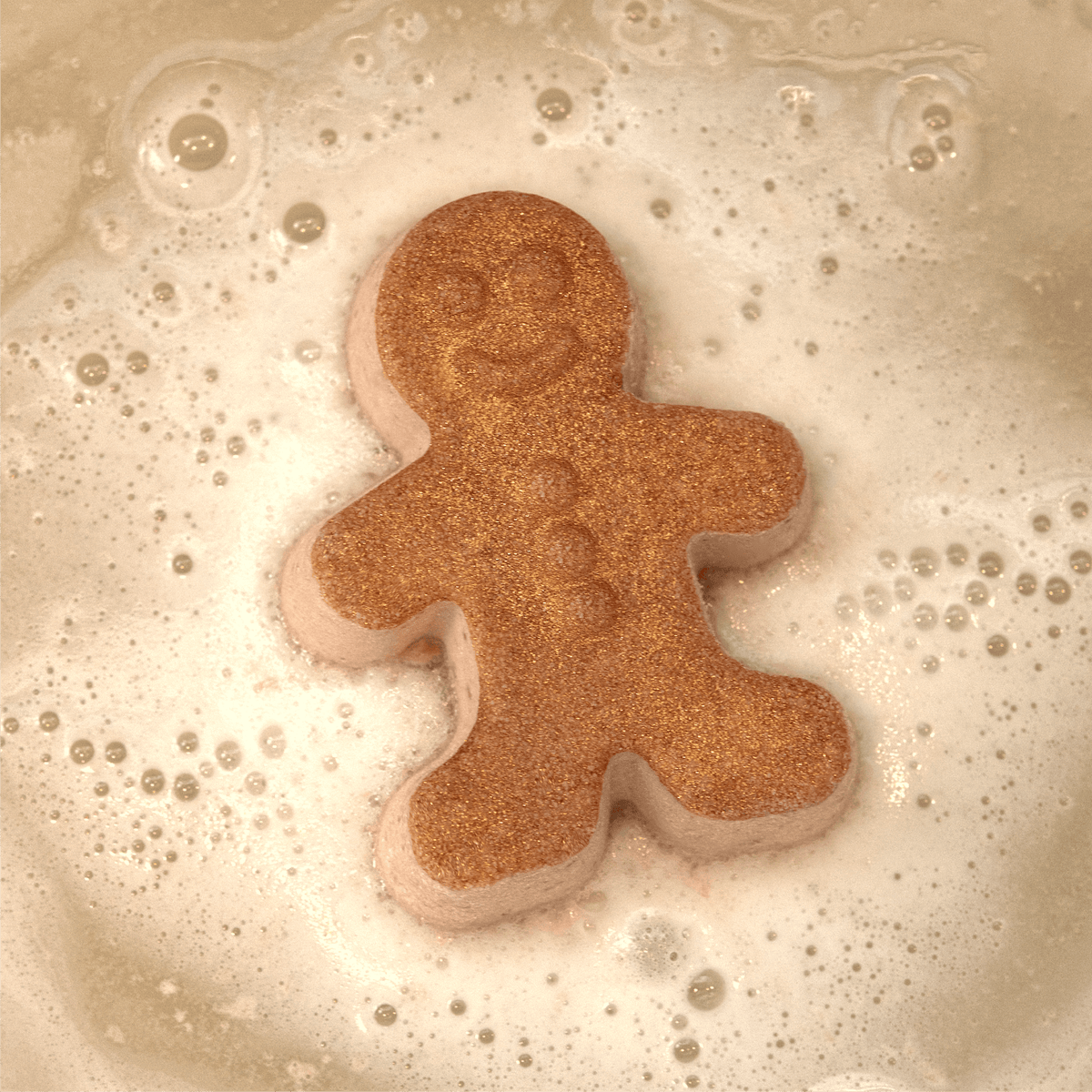 Pacha Soap's Handcrafted Bath Bomb "Vanilla Bean & Clove" in the shape of a gingerbread man and fizzling in the tub.