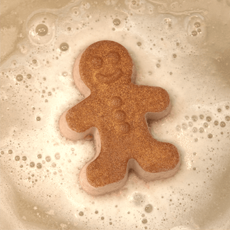 Pacha Soap's Handcrafted Bath Bomb "Vanilla Bean & Clove" in the shape of a gingerbread man and fizzling in the tub.