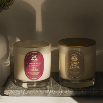 Pacha Soap Co's Pomegranate & Orange Peel and Vanilla Bean & Clove Signature Candles in a intense lighting and on a marble tray