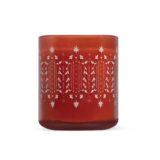 A translucent amber-red glass candle jar with a white etched holiday pattern of, snowflakes and holly leaves