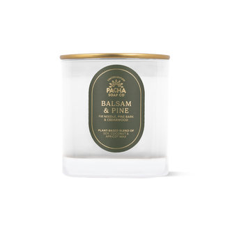 A clear glass jar candle with a gold metal lid and a dark olive green oval label reading 'PACHA SOAP CO. BALSAM & PINE'.