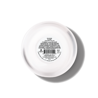 The bottom view of a round white glass jar with printed product information and a barcode