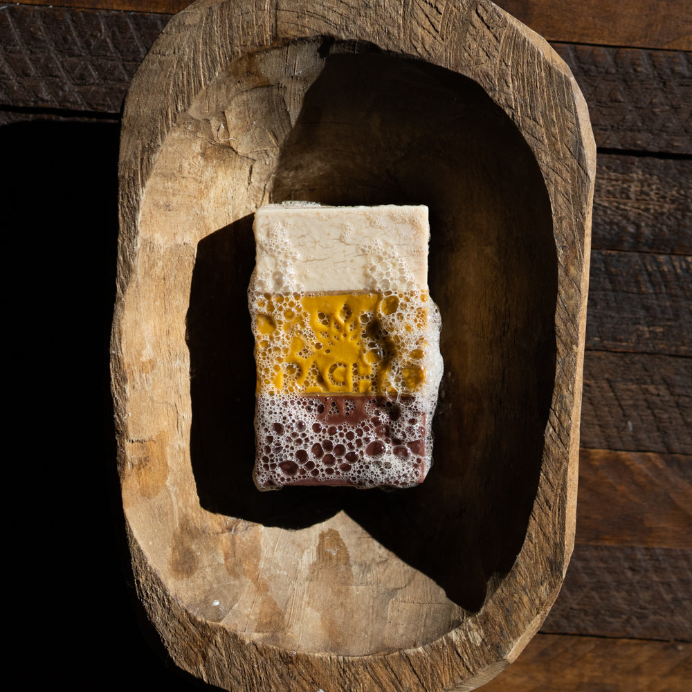 Frankincense Myrrh Bar Soap covered in bubbles in a wooden dish