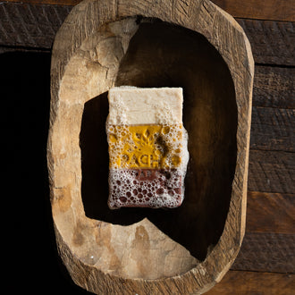 Frankincense Myrrh Bar Soap covered in bubbles in a wooden dish
